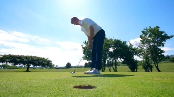 Golfboll faller i hålet efter att bli träffad av mannen — Stockvideo