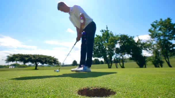 Un hombre está anotando un gol en el golf — Vídeo de stock