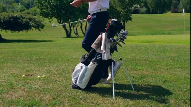 Um homem está a tirar um taco de golfe e a usá-lo. — Vídeo de Stock