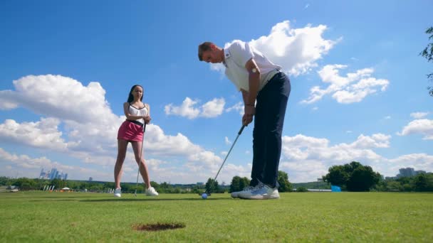 Una dama y un hombre juegan alegremente al golf. — Vídeos de Stock