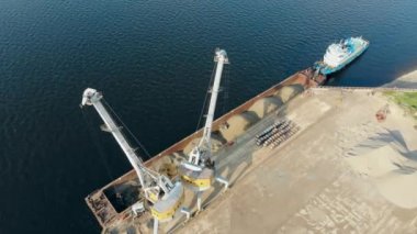 Bir vinç limanda çalışıyor, moloz la bir mavna boşaltma.