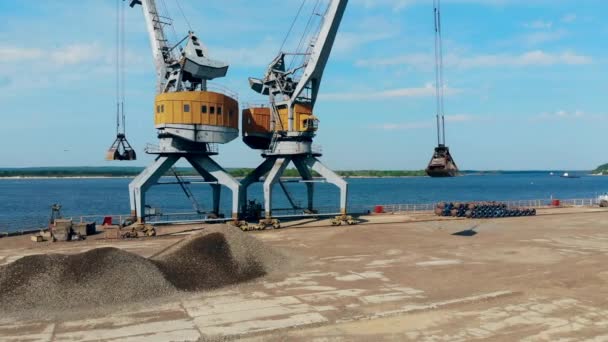 Una grúa lleva piedras en un cubo, trabajando en muelles . — Vídeos de Stock