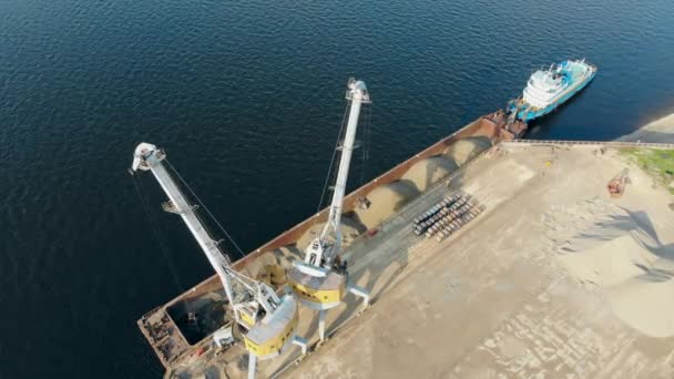 Une grue travaille dans un port, déchargeant une péniche avec des décombres .