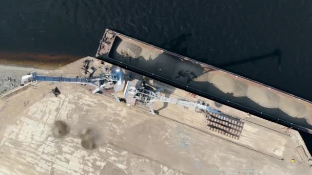 Duas máquinas de trabalho descarregam pedras esmagadas de uma barcaça na água . — Vídeo de Stock