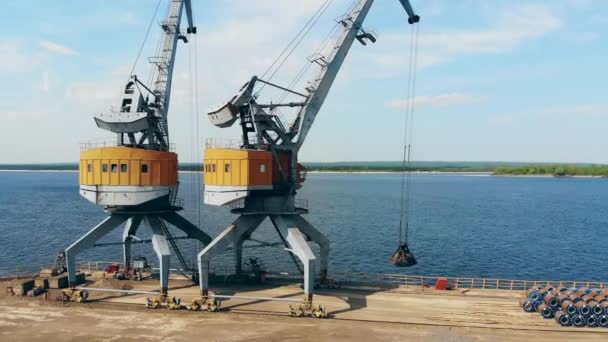 Grúa amarilla mueve piedras trituradas, trabajando en un puerto . — Vídeo de stock