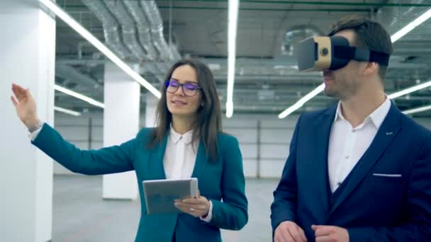 A man in VR-glasses and a real estate agent walking through the hall. Real-estate agent with client. — Stock Video