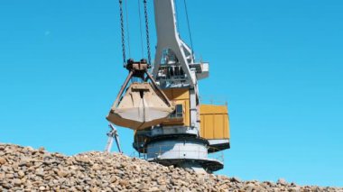 Sarı vinç metal bir kovada moloz taşır. Endüstriyel madencilik kavramı.