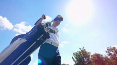 Bir adam golf aksesuarlarını toplayıp uzaklaşıyor.