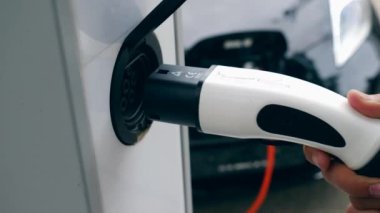 Bir adam elektrikli arabasını modern bir istasyonda şarj etti. Elektrikli araç şarj.