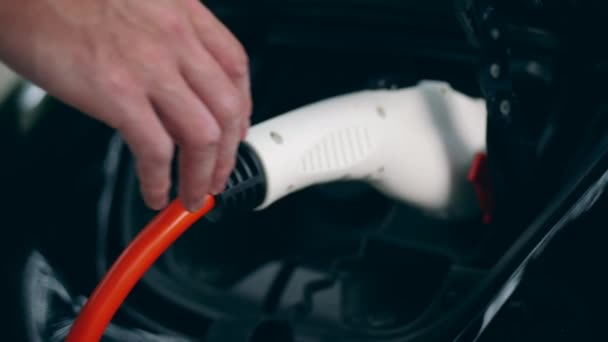 자동차 소유자는 전기 식 소켓에서 충전기를 분리합니다. 혁신적인 전기 하이브리드 자동차 충전. — 비디오