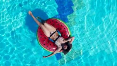 Bir otel havuzunda lastik halka üzerinde yatan genç kadın.