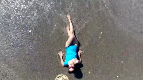 En kvinna njuter av vågor, liggande på en strand. — Stockvideo