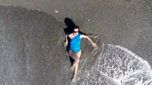 Ένα κορίτσι που βρίσκεται σε μια παραλία στο νερό κατά τη διάρκεια των διακοπών. — Αρχείο Βίντεο