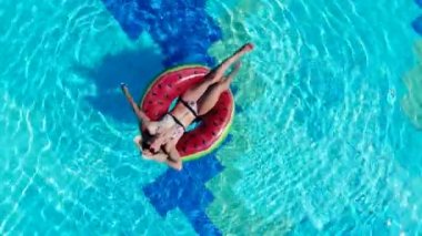 Bir kadın havuzda dinlenirken bir lastik halka üzerinde yüzer.