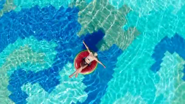 Una chica descansa en una piscina de hotel sobre un anillo de goma . — Vídeo de stock