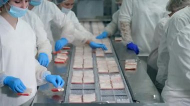 Fabrika konveyörü yakınında fabrika işçileri tarafından tutulan yengeç çubuklarının paketleme işlemi.