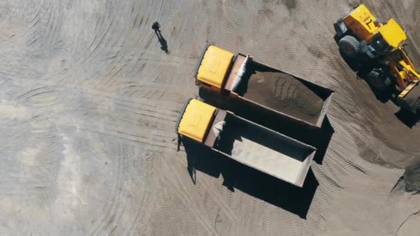 Carga de trator de trabalho dois caminhões com pedra esmagada. Conceito de mineração industrial . — Vídeo de Stock