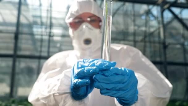 Female scientist is observing a tube with chemicals — Stock Video