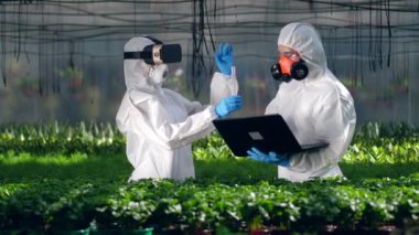 Bir biyolog bir tüp tutuyor ve başka bir uzmanla konuşuyor. Zehir, gıda kavramında pestisit.