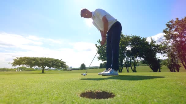 Golfspieler schlägt auf einem Golfplatz einen Ball in ein Loch. — Stockvideo