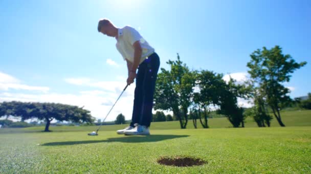 Golfista masculino chuta uma bola em um buraco enquanto pratica . — Vídeo de Stock