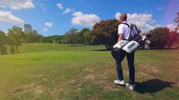 Persona camina en un campo de golf archivado, llevando una bolsa con equipo . — Vídeos de Stock