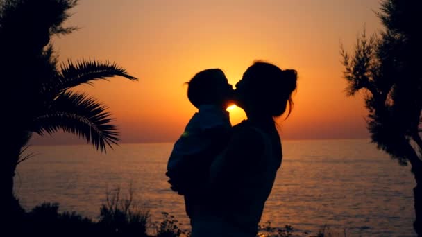 Mar al atardecer con una mujer besando a un niño — Vídeo de stock