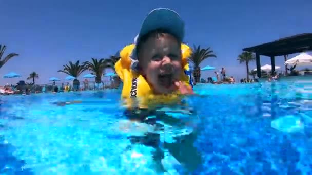 Enfant heureux dans un gilet de sauvetage nage dans la piscine — Video