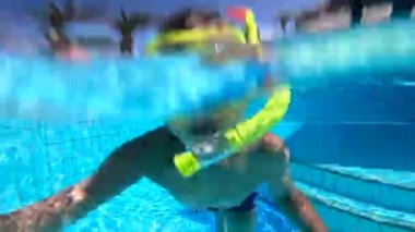 Dalış maskeli bir çocuk suya dalıyor ve ortaya çıkıyor.