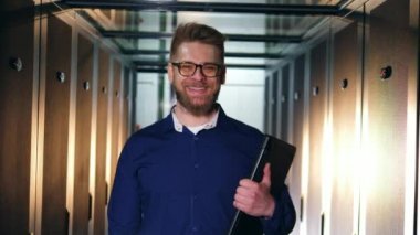 Bir mühendis kamera gülümsüyor, bir sunucu odasında ayakta.