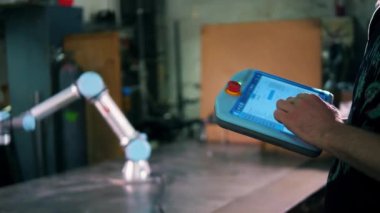 Tabletteki erkek tipleri, robotik bir kolu kontrol ediyor.