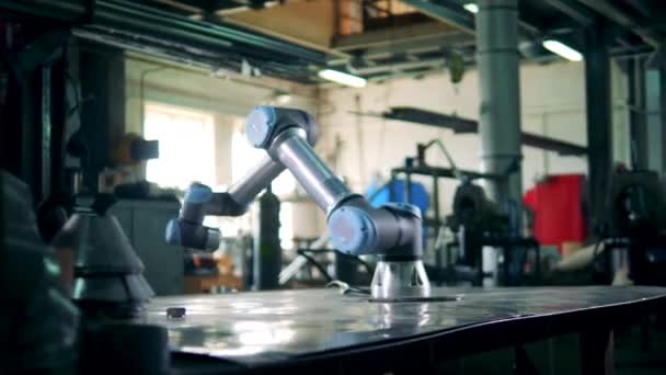 Een robot werkt met een versnelling op een tafel in een fabriek. — Stockvideo