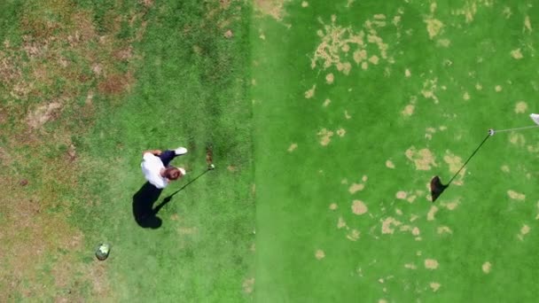 Una persona golpea una pelota mientras juega al golf en un campo . — Vídeos de Stock