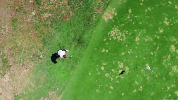 Un bărbat lovește o minge în timp ce joacă golf pe un teren . — Videoclip de stoc