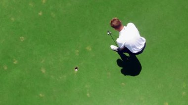 Golfçü bir golf alanında bir deliğe bir top vurur.