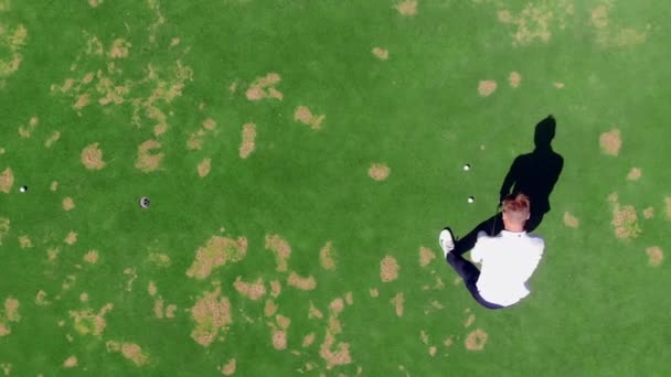 Człowiek stawia piłkę w otworze podczas gry w golfa na kursie. — Wideo stockowe