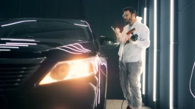 Elinde buffwheel ile erkek işçi bir arabanın yanında telefonda konuşuyor