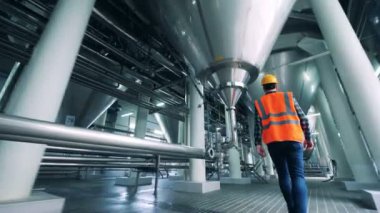 Erkek teknisyen damıtma ünitesi boyunca yürüyor.