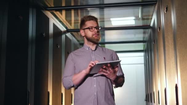 Male IT engineer with a tablet is observing servers — Stock Video