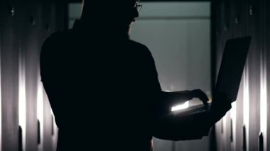 Dizüstü bilgisayarda yazan bir adamın karanlık silueti
