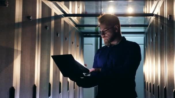 Specialista IT maschile sta gestendo un computer portatile in una sala server — Video Stock