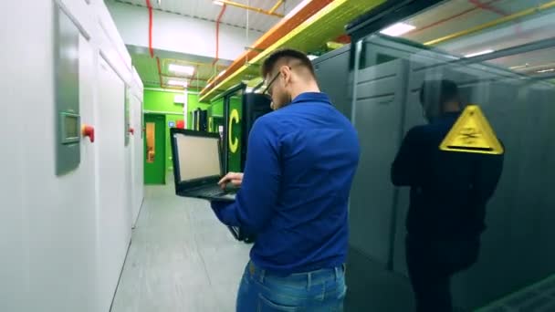 Homme technicien informatique marche le long de l'unité serveur — Video