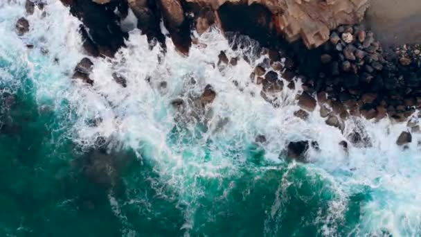 Zee spetteren tegen hoge rotsen aan een kust. — Stockvideo