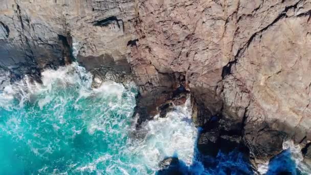 El mar de color turquesa salpicando contra las rocas en la costa . — Vídeos de Stock