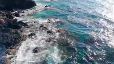 Dalgalar bir kıyıdaki yüksek kayalıklara giriyor.