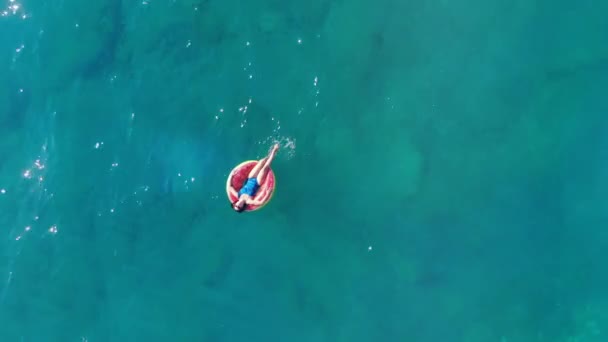 Genç kadın denizde yüzen, bir lastik halka üzerinde dinleniyor. — Stok video