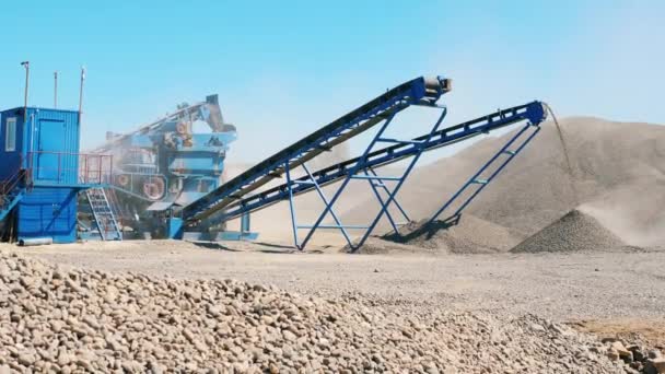 Aufbereiteter Kies ergießt sich aus der Mühle und liegt in Haufen. Bergbaugeräte im Steinbruch — Stockvideo