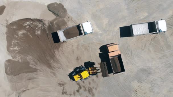 Vista superior de una excavadora llenando camiones con materiales de construcción — Vídeos de Stock