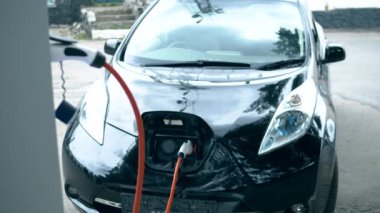 Siyah araba elektrikle şarj oluyor.