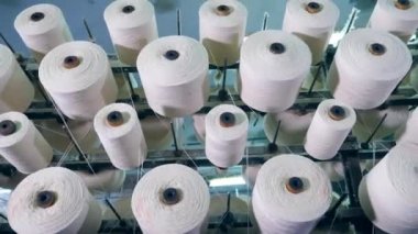 Tekstil fabrikası ekipmanları. Bobinler beyaz iplikler gevşeme ile dönüyor